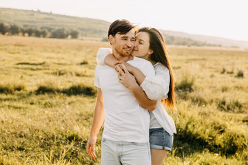 Young couple hugging and smiling outdoors in an open field on summer day.