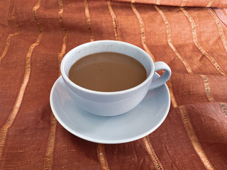 white cup of coffee on a red canvas