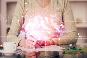 Double exposure of writing hand on background with brain hologram. Concept of learning.