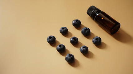 A bottle of blueberry seed essential oil and fresh blueberries on gold background