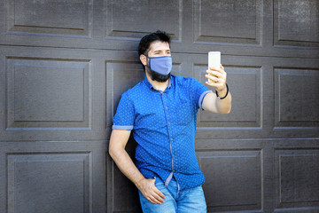 Smiling fashionable mature man taking selfie with protective face mask during covid-19 outbreak