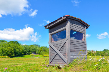old wooden house on a field near the forest and blue sky