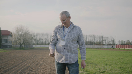 Portrait of a happy man farmer in nature checks the ground on field green meadow park adult agriculture garden male worker casual one person close up