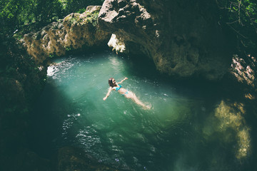 A woman in a swimsuit swims in a mountain river.