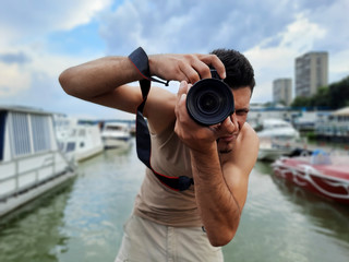 Photographer taking pictures at port with river, boats and yachts in the background
