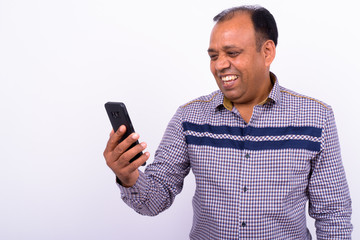 Portrait of happy mature overweight Indian businessman using phone