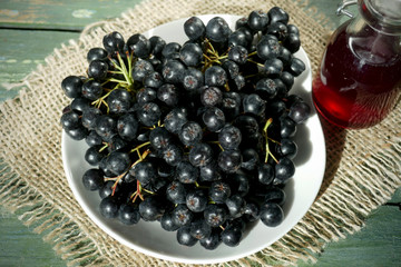 Fresh black chokeberry  (Aronia melanocarpa), juice in a bottle on a wooden background