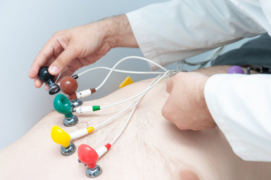 The cardiologist puts ECG sensors on the patient. Electrocardiography