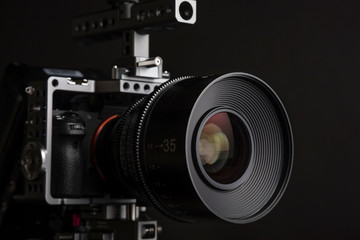Fototapeta na wymiar Medium closeup shot of professional cinematic camera setup including cage in black background with dramatic studio lighting