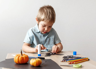 A cute little boy made a Halloween bat out of black paper. Children's handwork.