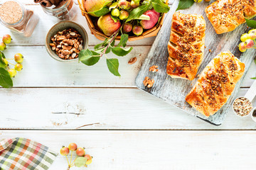 Baking with apple, Freshly baked apple and cinnamon rolls made from puff pastry on a white wooden table. Top view, rustic style, copy space.