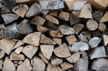 full-frame shot of stack of firewood, wood billets against wooden wall background