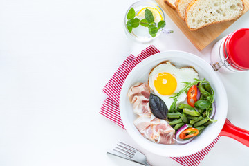 European breakfast: heart shaped egg, bacon, green beans on a white table. Selective focus. View from above. Copy space