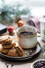 Homemade cookies with nuts and coffee in a ceramic cup on a wooden table with toys and Christmas tree branches