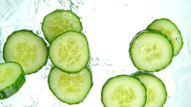 Super Slow Motion Shot of Cucumber Slices Falling into Water on White Background at 1000fps.