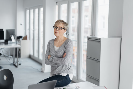 Woman with folded arms in office interior