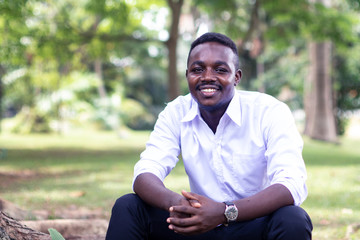 Fototapeta premium African business man sitting and smiling with green nature backgroung