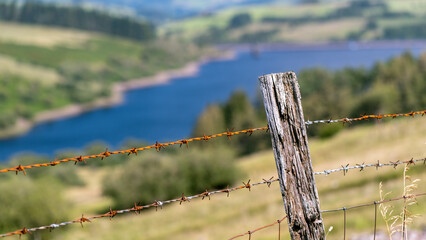 Wooden fence post with barbed wire overlooking Cray Reservoir 