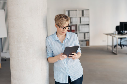 Relaxed woman standing reading on a tablet pc