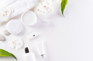 Cosmetic bottle containers, skin cream with green herbal leaves. Natural beauty and spa concept, Top view on white table background.