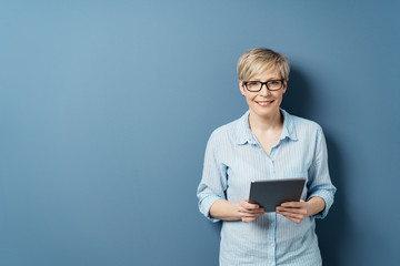 Smiling woman with tablet against blue background