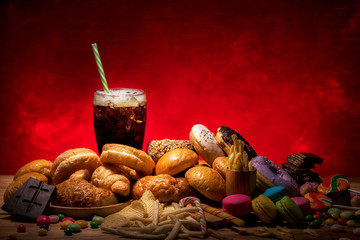assorted junk food multiple type that are dangerous to health on wooden table with copy space red...