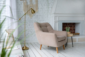 beige armchair in a bright room near the window,  fireplace