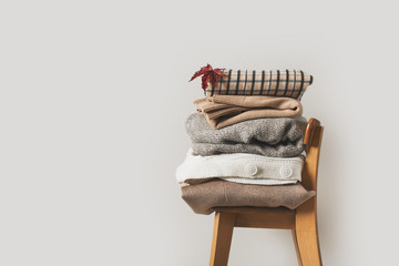 Autumn cozy and casual clothes stack close up on chair