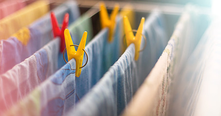 Colorful clean bed linen and towels after washing are hung on the bars of the dryer and secured with yellow and red clothespins. General cleaning, Laundry drying, compact dryer for the house.