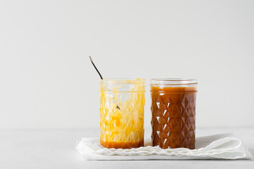 Liquid brown caramel in glass on white background