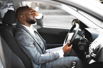 Exhausted african entrepreneur on a way home, driving car