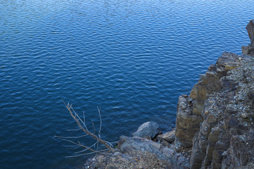Stone rocks near water, on the background of lake, river, sea, ocean. Blue clear water. Artificial reservoirs