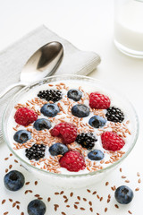 Yogurt with blueberries, raspberries, blackberries, flax seeds and a glass of milk. Served vegetarian dish. Healthy breakfast, healthy food.