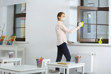the girl disinfects and wipes the window handles and ventilates the classroom