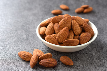 Almonds in a white bowl on black background,copy space.