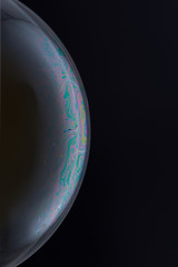 Current collection of brilliant backgrounds for your design. Close-up shot of a soap bubble with iridescent stains on the surface on the black backdrop. 