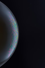 Current collection of brilliant backgrounds for your design. Close-up shot of a soap bubble with iridescent stains on the surface on the black backdrop. 