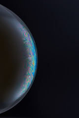 Current collection of brilliant backgrounds for your design. Close-up shot of a soap bubble with iridescent stains on the surface on the black backdrop. 