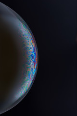 Current collection of brilliant backgrounds for your design. Close-up shot of a soap bubble with iridescent stains on the surface on the black backdrop. 