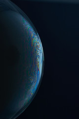 Current collection of brilliant backgrounds for your design. Close-up shot of a soap bubble with iridescent stains on the surface on the black backdrop. 
