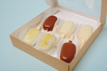 Chocolate cake in the form of ice cream on a stick on a white plate and a colored background