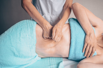 Young unrecognizable woman lying on massage table and enjoying therapeutic massage. Body care,...