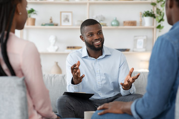 Confident black family counselor talking with married couple, giving advice to spouses - Powered by Adobe