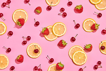 Red raspberry, strawberry, lemon colorful pattern on pink background. Fresh berry closeup, strawberry wallpaper, top view. Lemonade creative concept, fashionable trendy summer beverage, flat lay