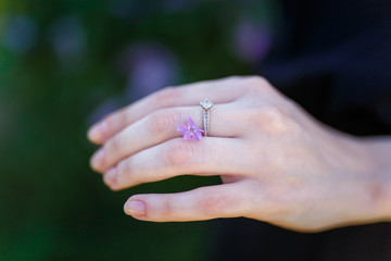 Female hand with tiny lilac flower between fingers. Tenderness and springtime blossom concept.