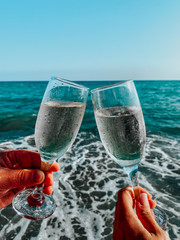 A couple celebrating a wedding date with the two glassess of wine on the beach