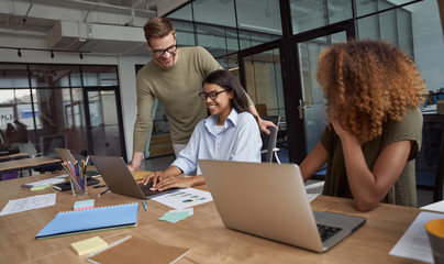 Group of happy colleagues, multiracial business team working sitting in the modern coworking space and working together, discussing something and smiling © Kostiantyn