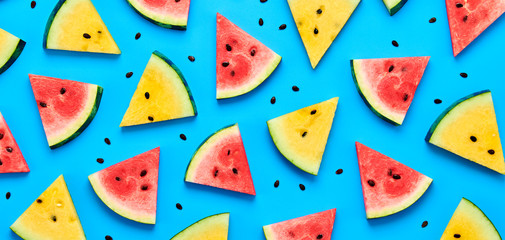 Watermelon colorful pattern on blue background. Fresh red yellow watermelon slices closeup, wallpaper, top view. Creative summer concept, fashionable trendy flat lay