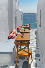 The narrow path to the sea with furniture at Mykonos island in Greece