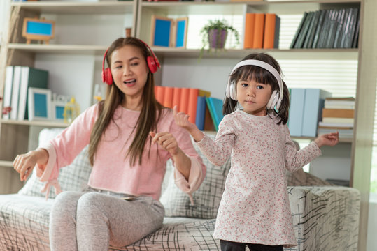 Happy Asian Child Having Fun And Dancing With Her Mother In A Room